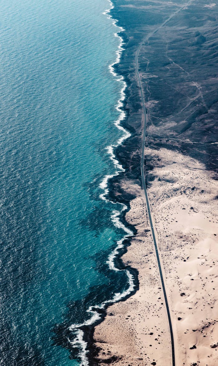 A breathtaking aerial view of the rugged Fuerteventura coastline with turquoise waters meeting sandy shores.