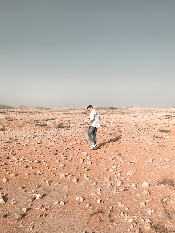 A man walks across a rocky desert landscape in Spain's Fuerteventura, showcasing solitude and vastness.