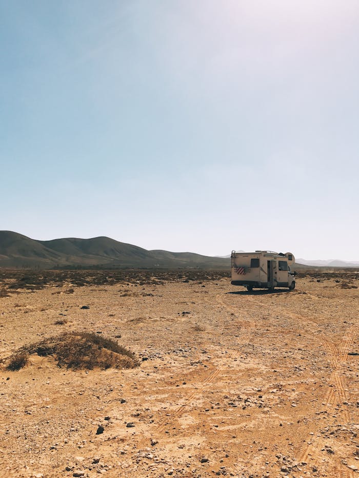 Explore the vast desert landscape of La Oliva, Spain with a solitary camper van under a clear blue sky.